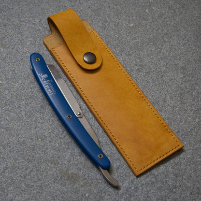 Blue straight razor with yellow leather sheath on a grey surface