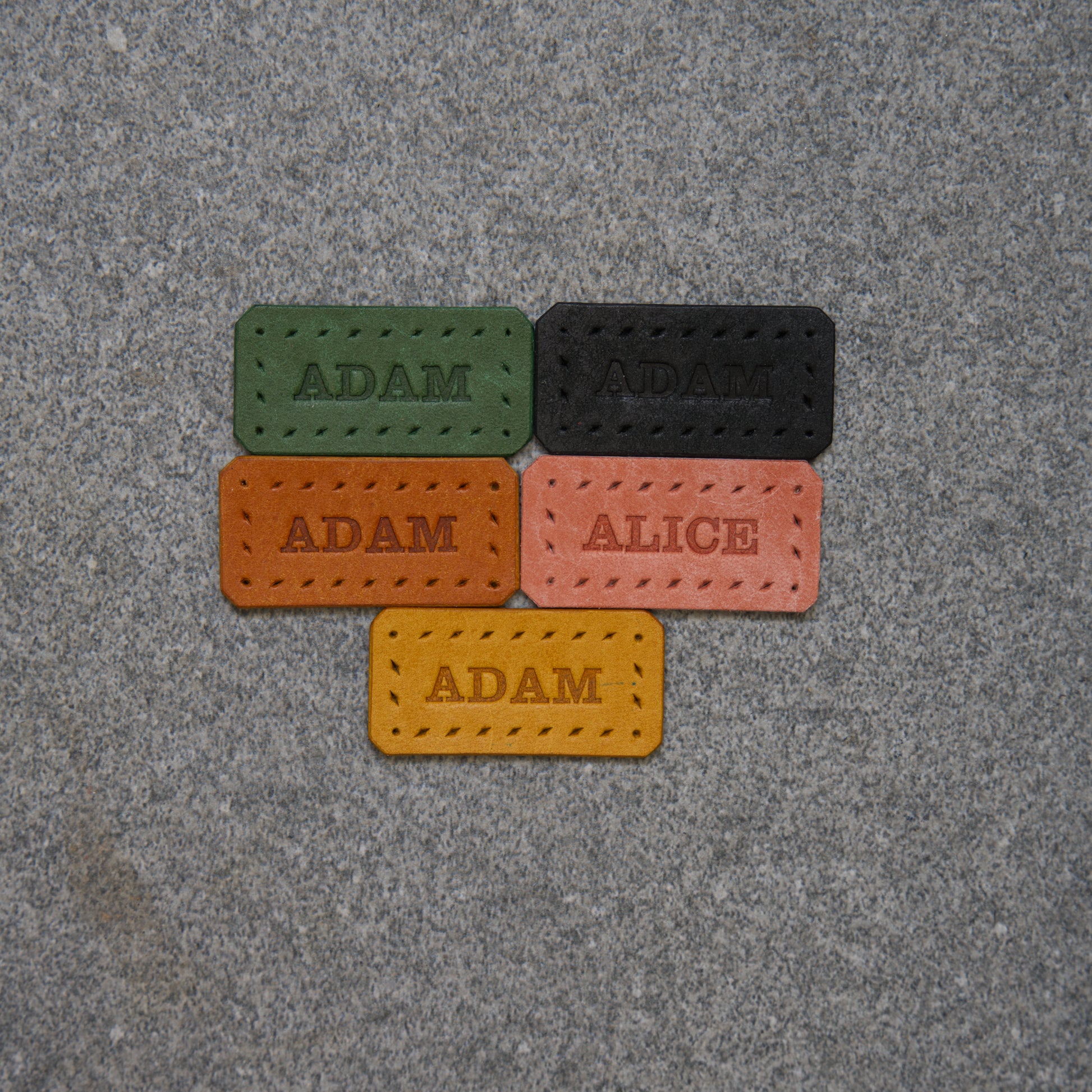 Five name tags with names 'Adam' and 'Alice' on a textured surface